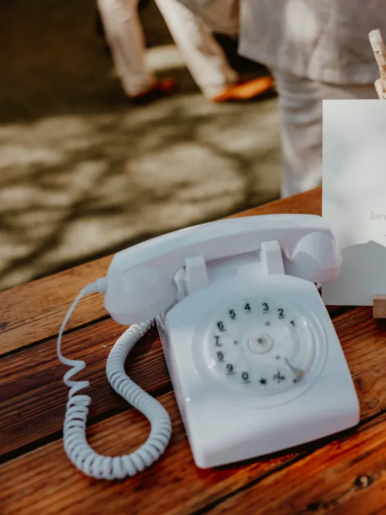 The vintage white rotary phone audio guest book set up on a wooden table