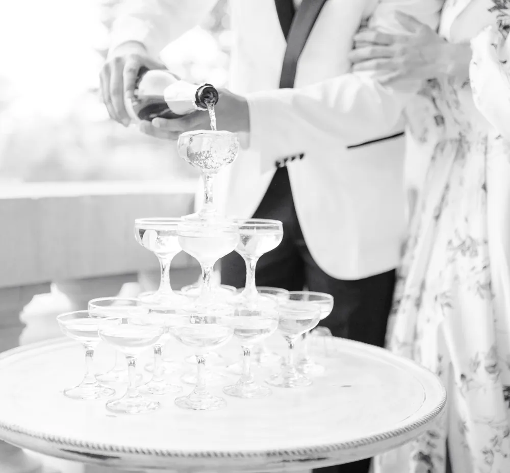 A champagne tower being poured at a wedding reception