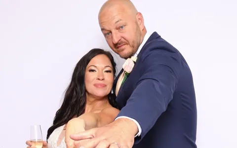 A bride and groom showing their rings in the photo booth