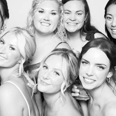 A black and white photo booth portrait of a wedding party against a white backdrop