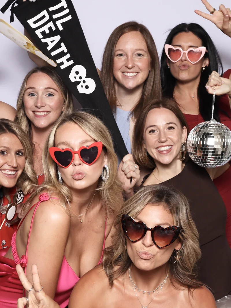 Wedding guests crowded into the Viva Booth Co. photo booth in heart sunglasses
