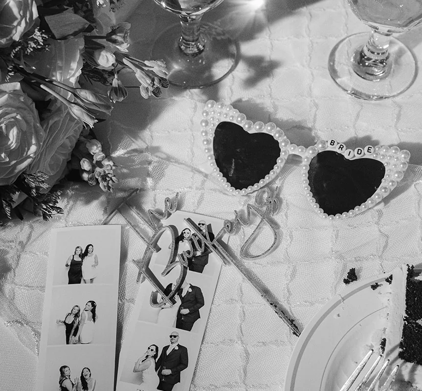 Black and white film strips beside heart sunglasses and flowers on a wedding reception table
