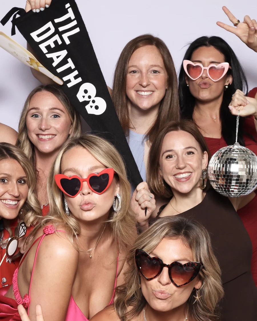 Guests posing together in the Viva Booth Co. photo booth in heart shaped sunglasses