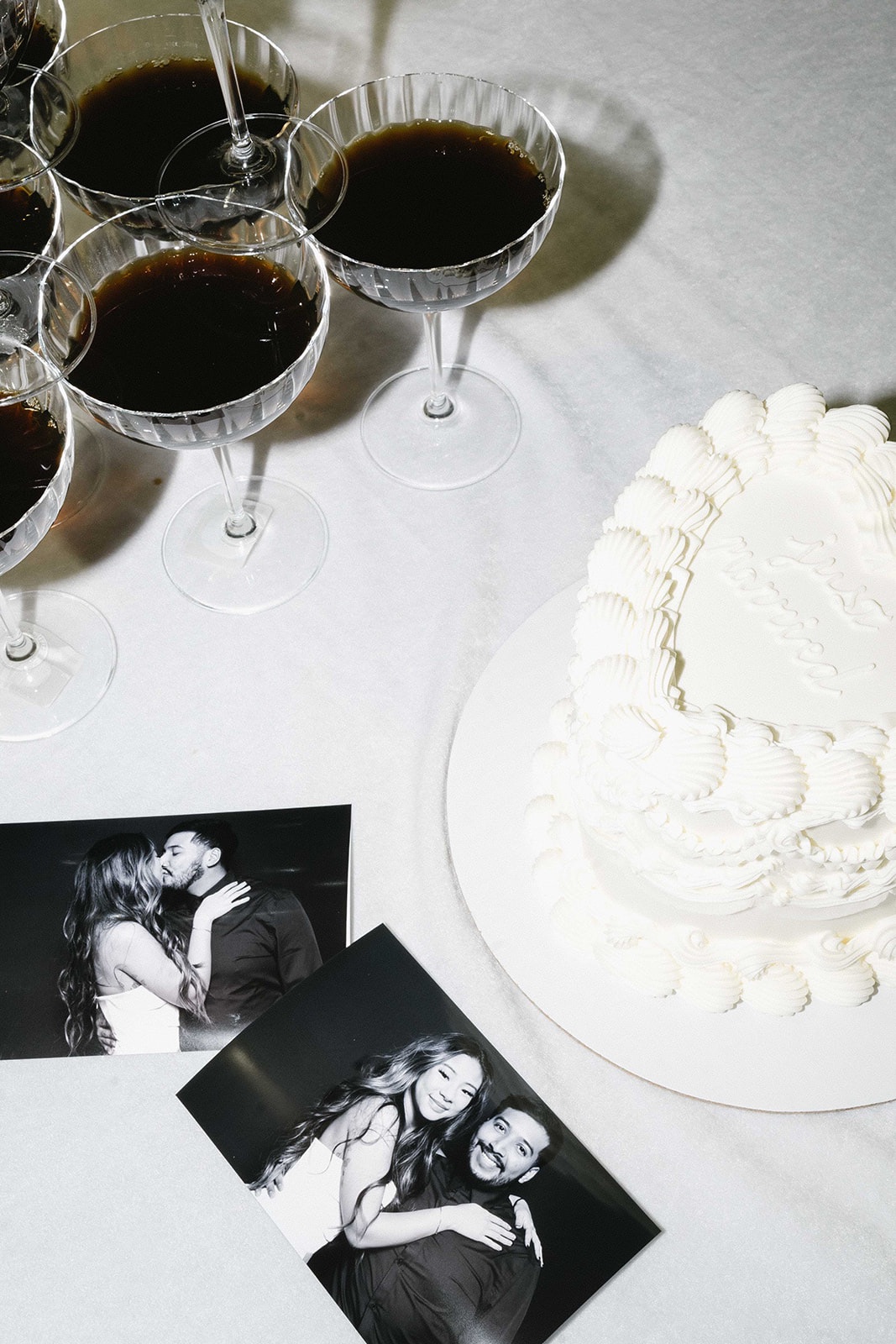Black and white photo booth prints beside a heart shaped cake and espresso martinis