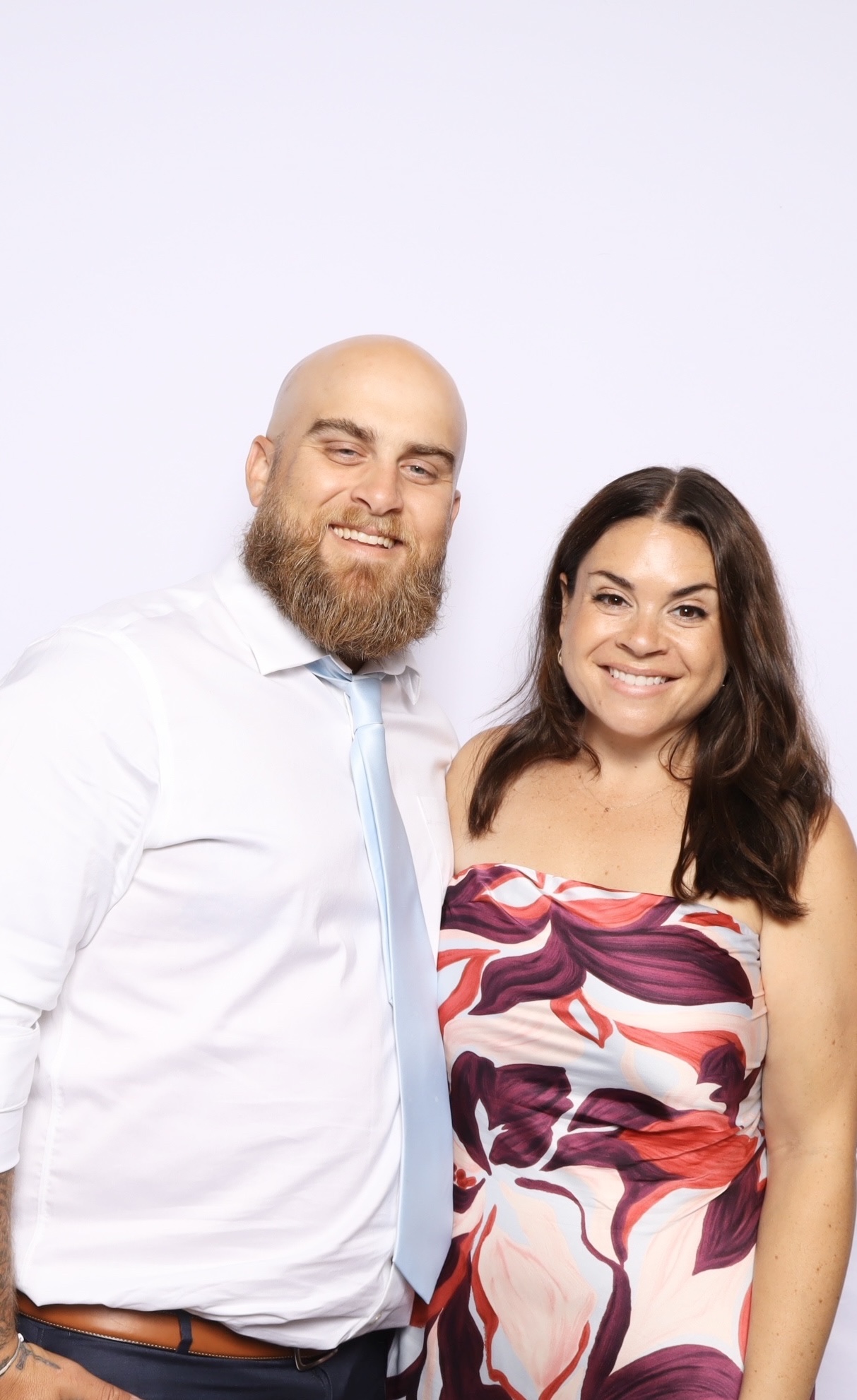 Two guests smiling together against a soft plain backdrop in the open air booth