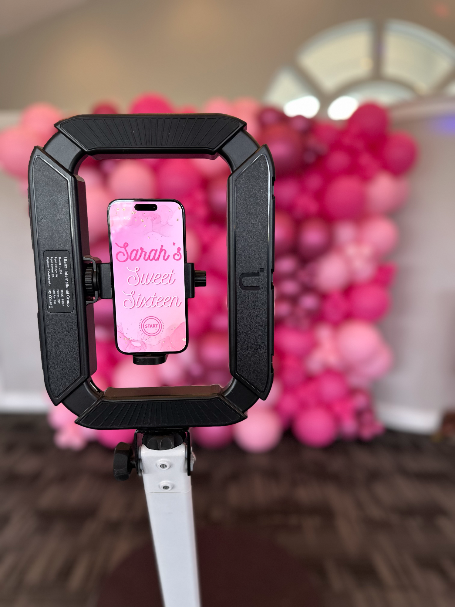 The booth showing a custom Sweet Sixteen start screen in front of a pink balloon wall